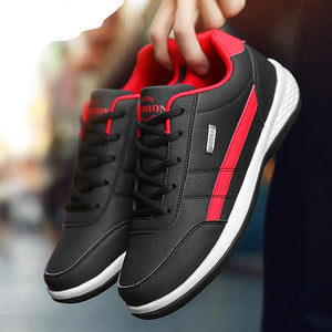Black and red sneakers with white soles held by a hand.