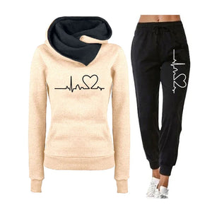 Beige hoodie with black heart design and black jogger pants on a white background