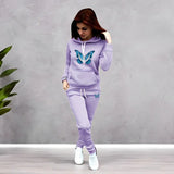Woman wearing a lavender tracksuit with butterfly designs against a gray background