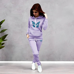 Woman wearing a lavender tracksuit with butterfly designs against a gray background