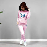 Woman wearing a pink tracksuit with butterfly designs on a gray background