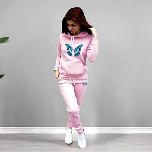 Woman wearing a pink tracksuit with butterfly designs on a gray background