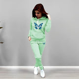 Woman wearing a light green tracksuit with butterfly designs on a gray background