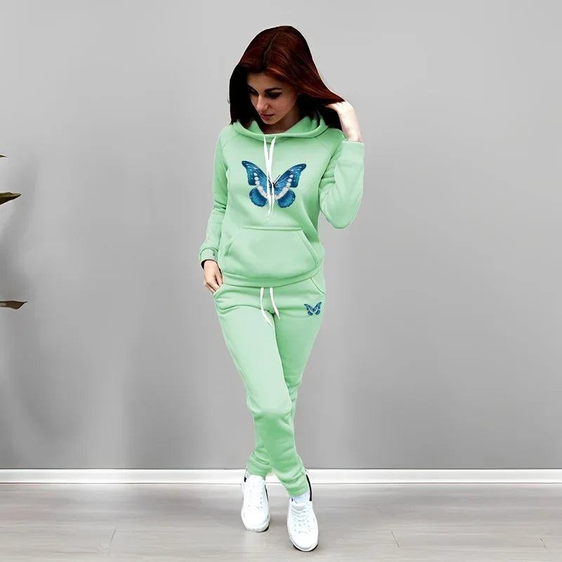 Woman wearing a light green tracksuit with butterfly designs on a gray background